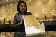 An employee at a jewellery store displays gold chains in Singapore in 2011. Singapore will exempt investment-grade gold and other precious metals from the goods and services tax in a move to turn the city-state into a gold trading hub, the finance minister said Friday