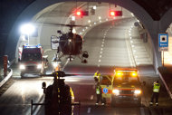 A rescues helicopter is airborne as rescue worker stand in front of the tunnel entrance after a bus crashed in the tunnel, in Sierre, Switzerland, early Wednesday, March 14, 2012. According to media reports 28 people have been killed when the bus from Belgium crashed inside the tunnel. 