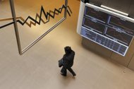 A woman walks under an electronic index display at the Athens stock exchange on March 9. Greece's economy is expected to exit recession only by 2014, the International Monetary Fund said Thursday after announcing a new bailout loan for the heavily indebted country. 