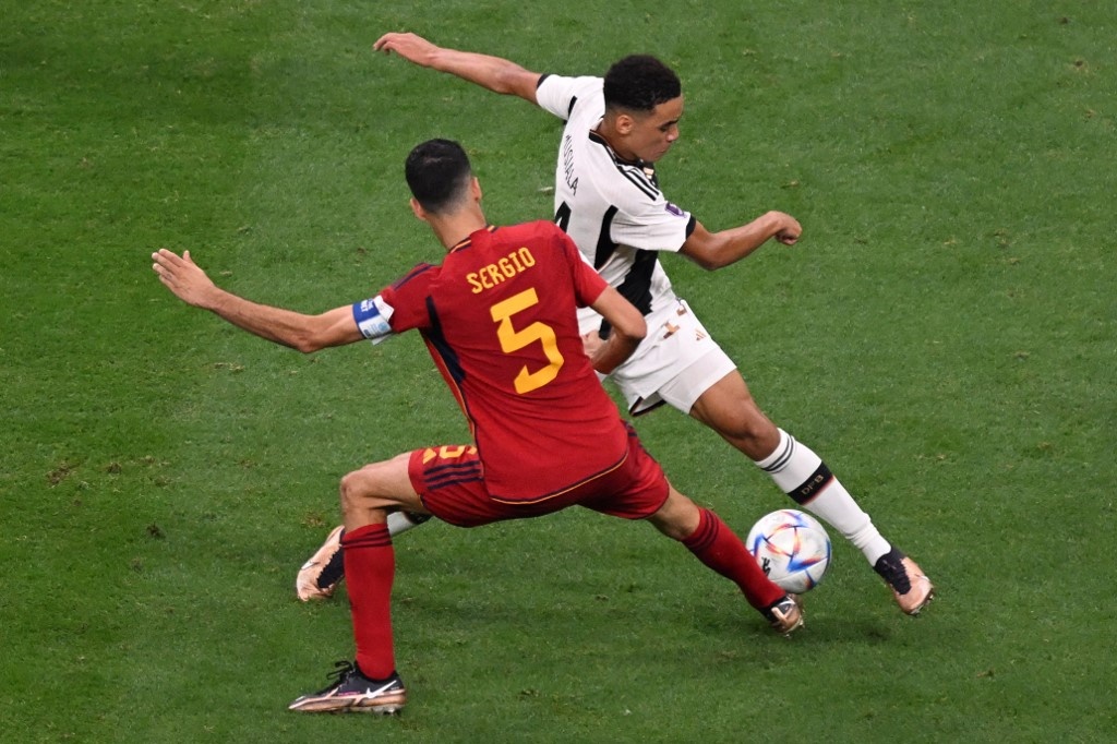Spain's midfielder #05 Sergio Busquets marks Germany's midfielder #14 Jamal Musiala during the Qatar 2022 World Cup Group E football match between Spain and Germany at the Al-Bayt Stadium in Al Khor, north of Doha on November 27, 2022. Photo Kirill KUDRYAVTSEV / AFP
