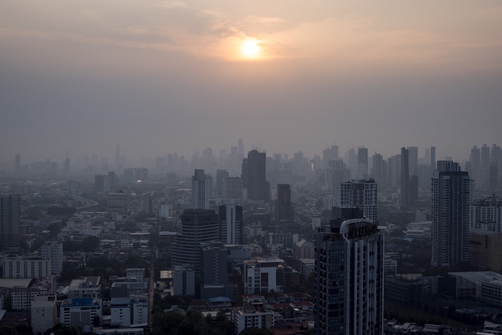 This picture shows buildings amid air pollution as the sun sets in Bangkok on April 17, 2023. Jack TAYLOR / AFP
