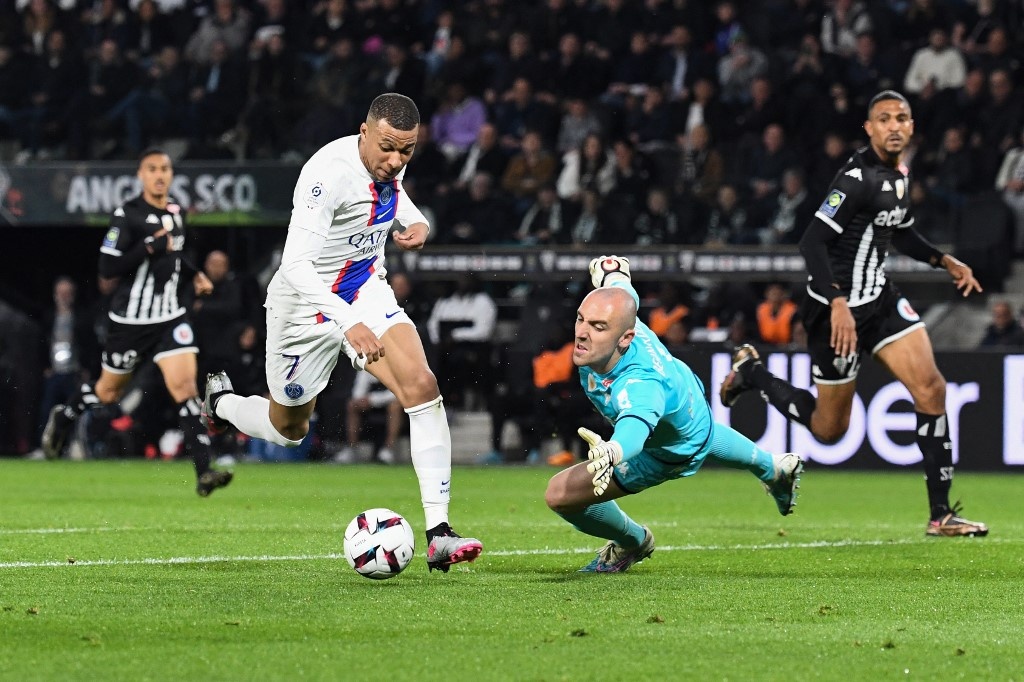 Paris Saint-Germain's French forward Kylian Mbappe (L) shoots and scores his team's second goal against Angers' French goalkeeper Paul Bernardoni during the French L1 football match between SCO Angers and Paris Saint-Germain (PSG) at The Raymond-Kopa Stadium in Angers, western France on April 21, 2023. JEAN-FRANCOIS MONIER / AFP
