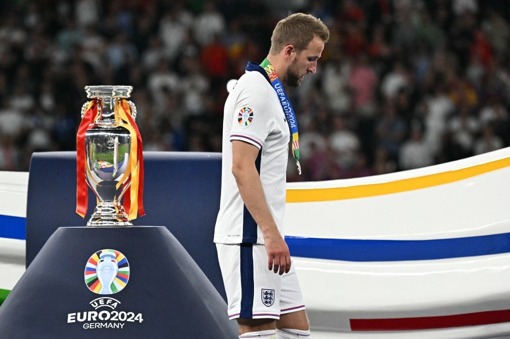 England's forward #09 Harry Kane receives a silver medal and walks past the trophy at the end of the UEFA Euro 2024 final football match between Spain and England at the Olympiastadion in Berlin on July 14, 2024. JAVIER SORIANO / AFP