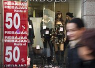 People walk past a shop window on January 2, 2012 on the first day of winter sales in Madrid. Spanish retailers are offering deep discounts in their post-Christmas sales to try to get cash-strapped shoppers to open their wallets as a sharp economic downturn drags painfully on.