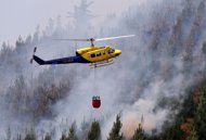 A helicopter carries a water bag to fight a massive forest fire affecting the commune of Ranquil, in southern Chile's Biobio region on January 4, 2012. Authorities suspect several fires that erupted almost simultaneously were the work of criminals.