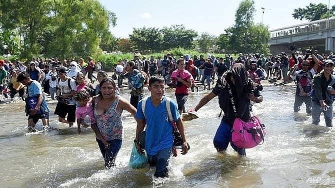troops fire gas as migrants try to storm into mexico