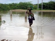 A woman, carrying a baby, wades through the water covering a bridge connecting the suburbs in the outskirts of Chokwe, near the Limpopo river in southern Mozambique, January 26. The World Food Programme (WFP) will give emergency food to more than 80,000 people in Mozambique after twin cyclones left 32 dead in the impoverished country in January, officials said Tuesday. 