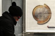 A woman walks by a sign showing a euro coin at a bank branch in Athens, on January 31. Banks locked in negotiations with Greece for a debt write-off deal expressed hopes for an accord in coming days amid 