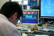 A trader looks at computer screens scrolling financial markets curves in Paris, 2010. European stock markets rose robustly on Thursday on optimism that the Greek debt swap would be successful.