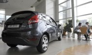 Customers sit beside a new Ford car on display at a dealership in Beijing, 2009. Vehicle sales in China, the world largest auto market, rose sharply in February from a year earlier, an industry group said, but were capped by the Lunar New Year holiday