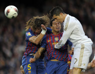 Barcelona's Carles Puyol (L) and Thiago Alcantara (C) jump for the ball against Real Madrid's Cristiano Ronaldo during the Spanish League 