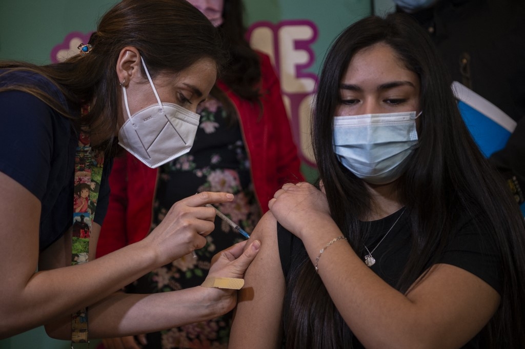A health worker administers a dose of the Pfizer-BioNTech vaccine against COVID-19 to a minor at a vaccination centre in Santiago, on June 23, 2021. Chile began inoculating children from 12-years-old against COVID-19. Martin BERNETTI / AFP