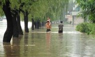 Image provided by North Korea's official Korean Central News Agency shows people walking down a flooded road in Anju city in North Korea's South Phongan province. A United Nations team will visit flood-hit areas of North Korea to consider possible aid, a UN official said on Tuesday after Pyongyang reported scores dead and tens of thousands homeless