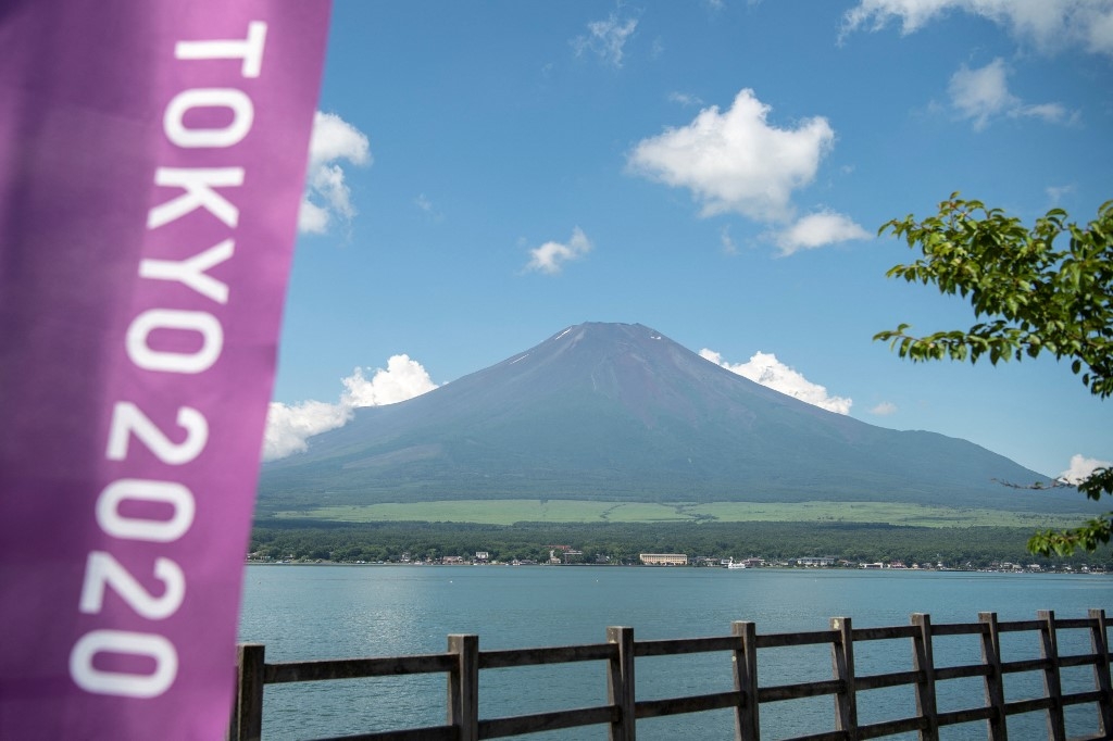 This general view shows Mount Fuji, Japan's highest mountain at 3,776 meters (12,388 feet), seen from Lake Yamanaka, next to a Tokyo 2020 Olympics banner on July 19, 2021. Charly TRIBALLEAU / AFP