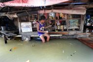 A boy makes a purchase in a flooded convinient store in Manila. Four people were killed as another tropical storm swept across the Philippines on Wednesday, triggering landslides in the mountainous north and dumping more heavy rain on the flood-battered capital