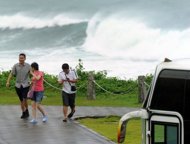 Chinese tourists walk near the coast of Hualien, eastern Taiwan, on August 23, 2012. Typhoon Tembin made landfall in Taiwan early Friday, toppling trees and ripping off rooftops in exposed areas in the south of the island, officials said