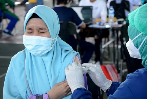 A woman receives the Sinovac Covid-19 coronavirus vaccine during a mass vaccination at Praja Raksaka Udayana Military Regional Command in Denpasar, on Indonesia's resort island of Bali on August 4, 2021. SONNY TUMBELAKA / AFP