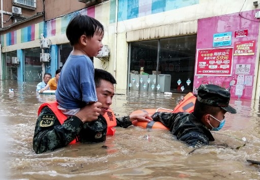This photo taken on August 12, 2021 shows rescuers evacuating a child from a flooded area following heavy rains in Suizhou, in China's central Hubei province. CNS / AFP