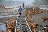 Two boys cross a bridge at Kapay river in a remote area in Philippines' Iligan City on December 26. The death toll from killer floods in the Philippines surged by more than 200 on Tuesday, more than a week after the disaster struck, with officials expecting more corpses to be found